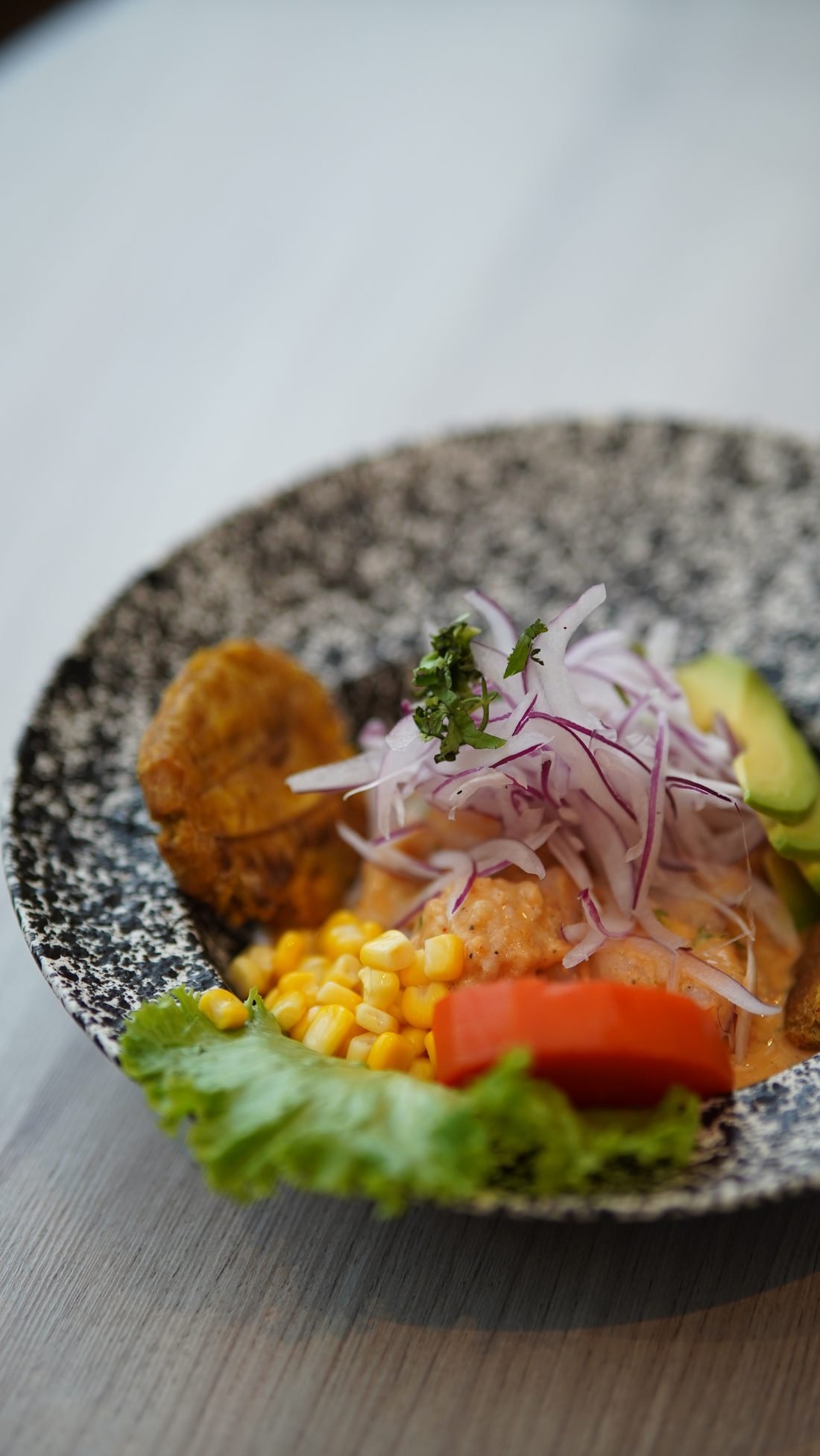 Ceviche servido con tostones, elote y ensalada fresca